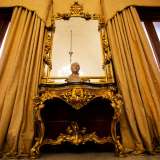 Una parete � occupata da due alte porte-finestre e una consolle settecentesca con specchiera intagliata a mano... 